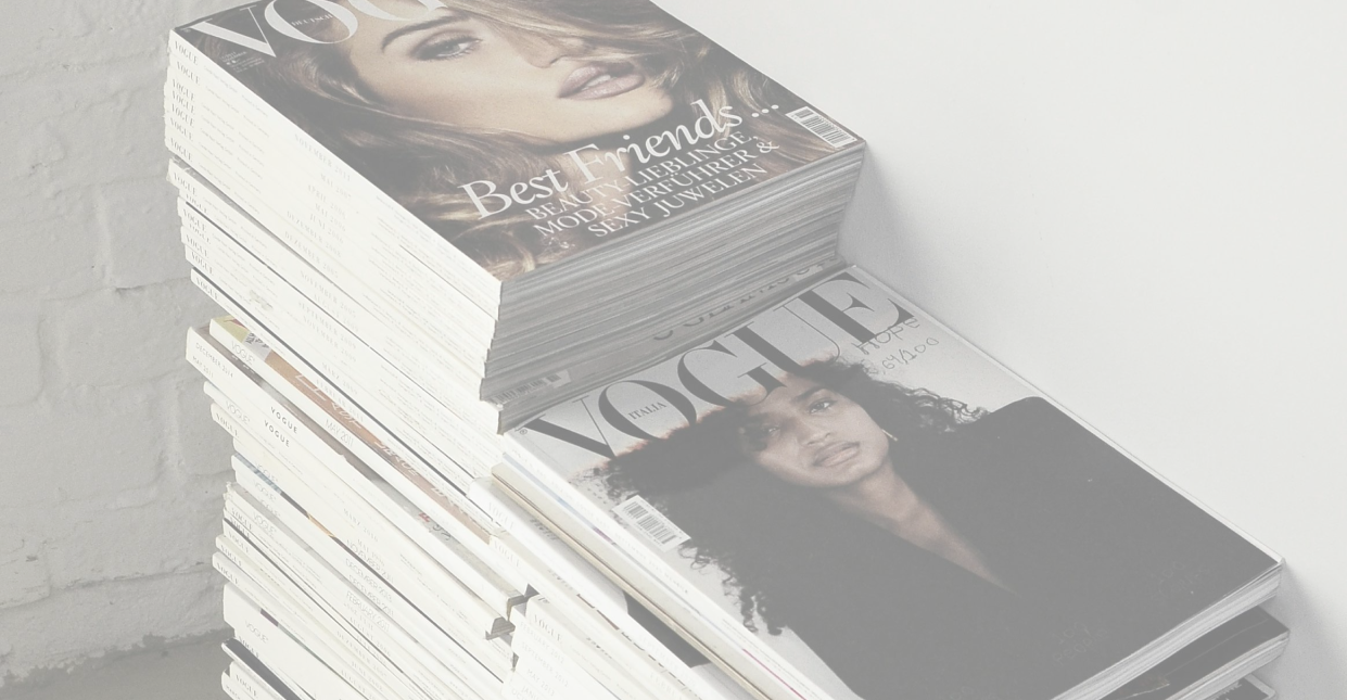 Dozens and dozens of fashion magazines stacked in a pile
