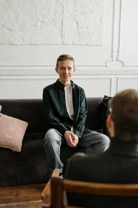 A young man sitting on a couch, engaging with a coach