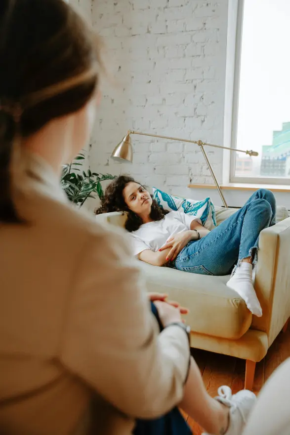 A young woman relaxed on a couch, talking with a coach