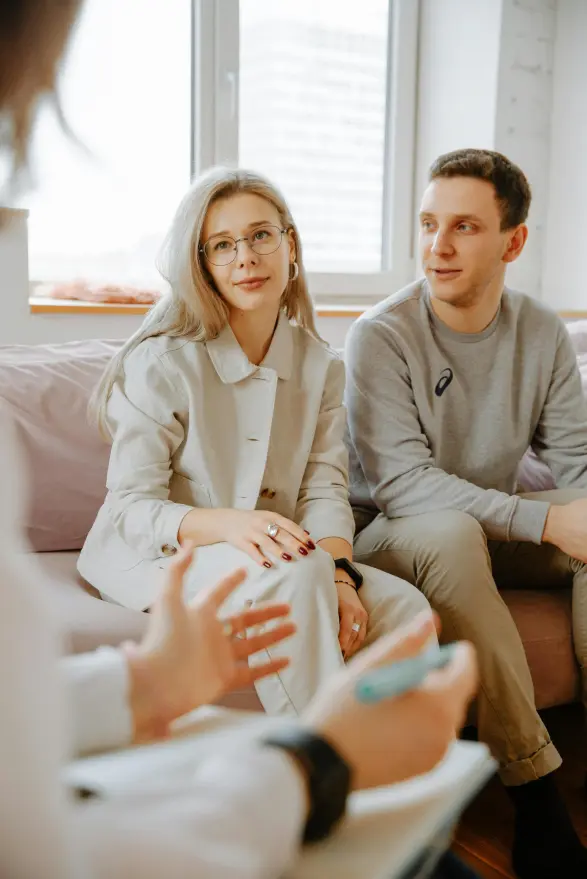 A couple sitting on a couch, talking with a coach